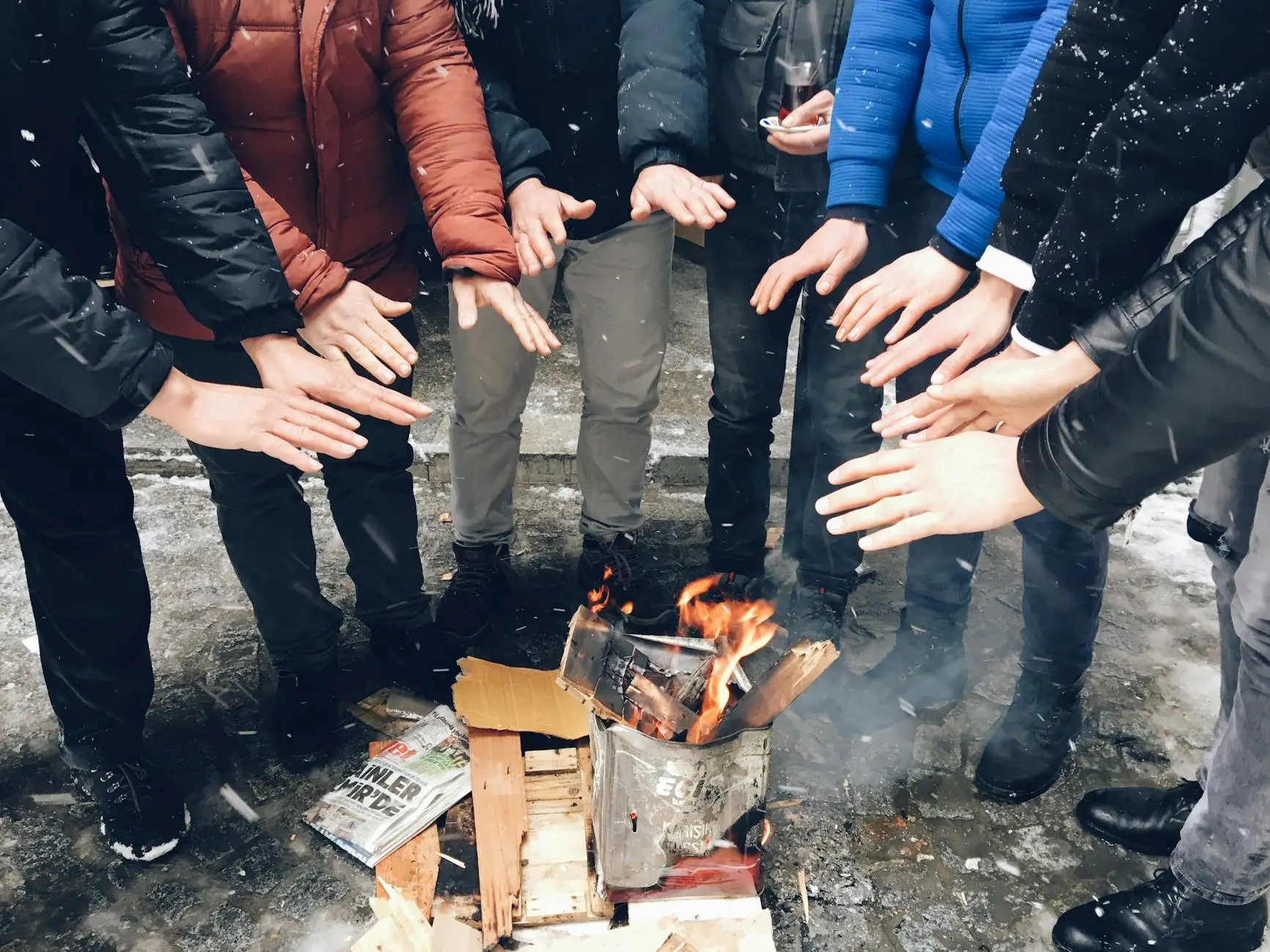 group warming hands over outdoor fire in winter